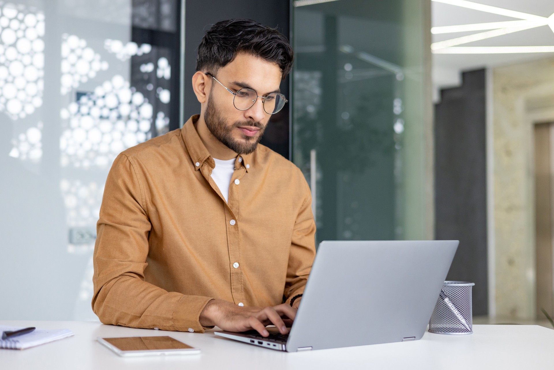 Focused man working on laptop in modern office environment